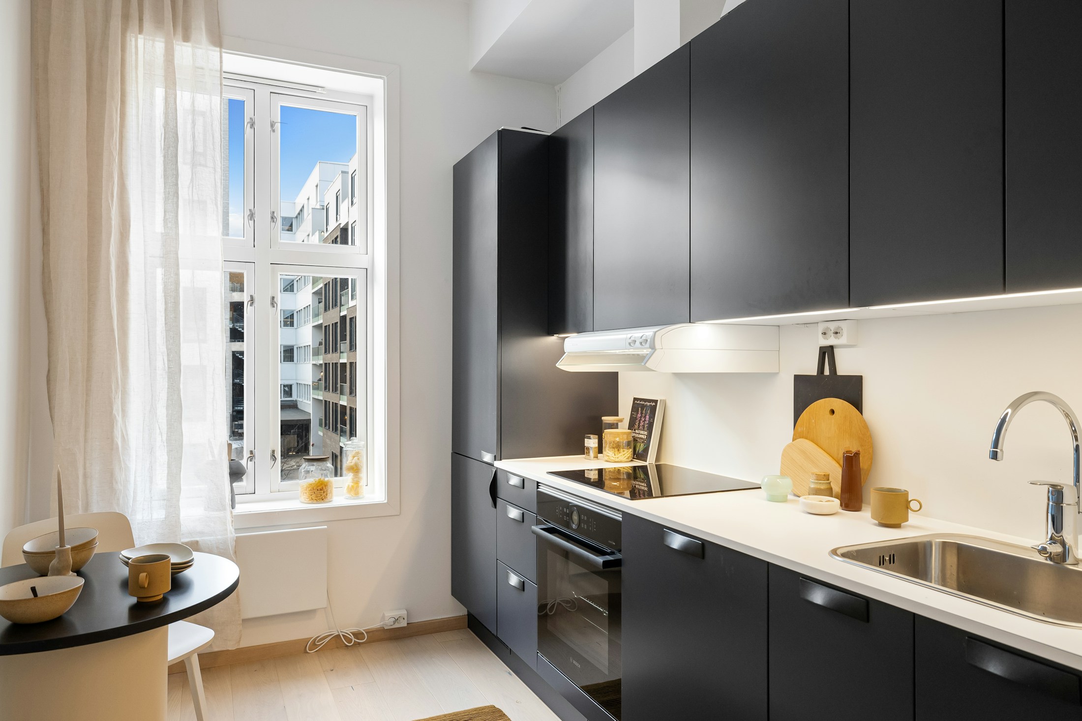 Considered kitchen with dark cabinets, warm timber and bright natural light